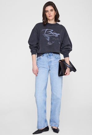 Woman in black trench coat with graphic sweatshirt and jeans