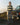 Person standing in front of a vintage Rover car by a scenic coastal road.