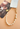 A gold and white baroque pearl phone strap with a lobster clasp, shown attached to a clear phone case on a peach-colored background.